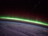 Ein von der ISS aufgenommenes Foto zeigt einen grünen Polarlichtbogen über den Wolken.