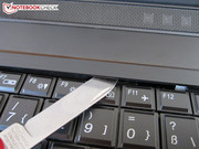 Mit einem flachen Objekt gelangt man an die Schrauben der Tastatur.