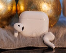 Apple Airpods 4 auf Teppichflor vor goldenen Kugeln