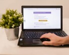 Laptop auf einem Tisch zeigt eine Phishing-Mail mit einem Bestätigungs-Knopf